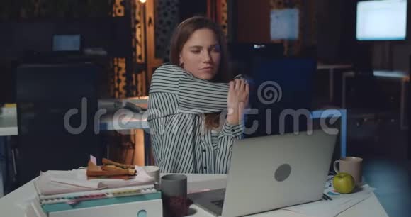 年轻女性办公室工作人员在办公室里使用笔记本电脑时伸展身体的正面视图很漂亮的女孩工作视频的预览图