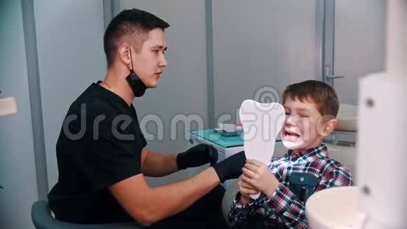 一个在牙科治疗的小男孩照镜子的男孩视频的预览图