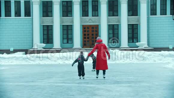 一家年轻的母亲和两个孩子在户外的公共冰场上滑冰视频的预览图