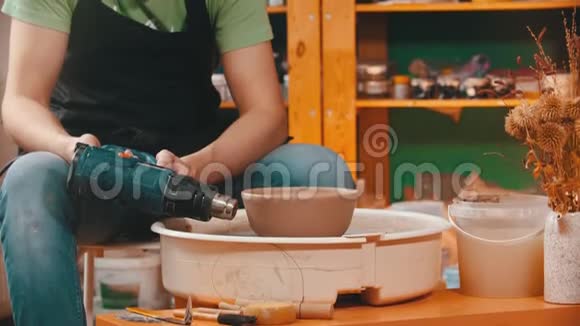 陶器主人正在用建筑吹风机烘干粘土碗视频的预览图