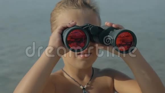 小男孩用双筒望远镜观看模糊海洋的慢镜头视频的预览图