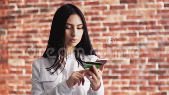 一个脸严肃的女孩把银行卡数据输入手机一个十几岁的女孩把钱从银行卡里捐给视频的预览图