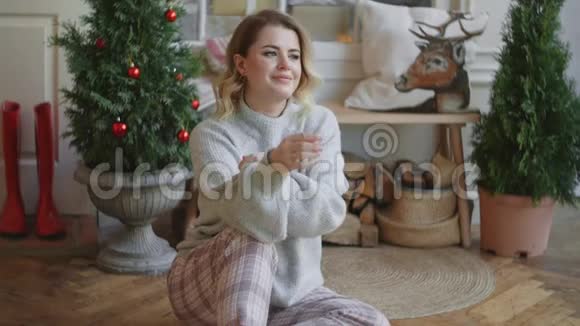 欧洲年轻迷人的女士穿着温暖的毛衣坐在斯堪的纳维亚内部舒适的圣诞家庭氛围和舒适的家庭氛围视频的预览图