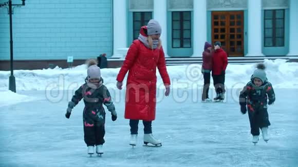 一位年轻的金发女人和她的孩子们在冰上滑冰视频的预览图