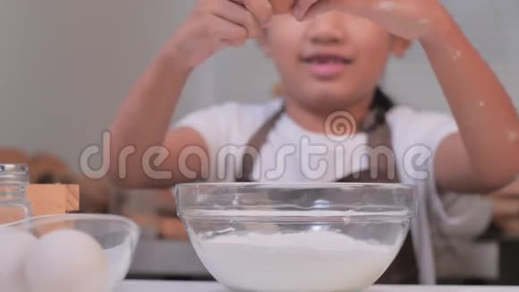 慢动作视频一个亚洲小女孩把鸡蛋钉在一个面粉碗里做面包店视频的预览图