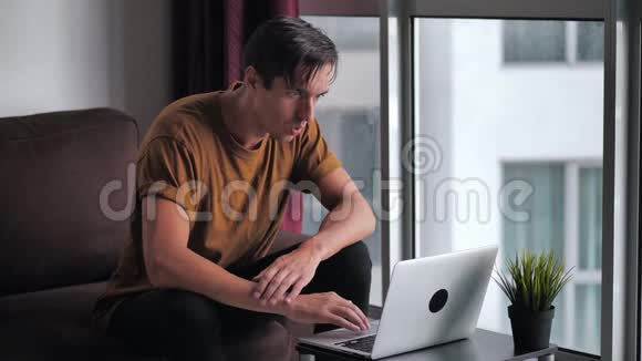 害怕的人被他在家里坐在桌子旁看到的笔记本电脑所震惊和不愉快的惊讶视频的预览图