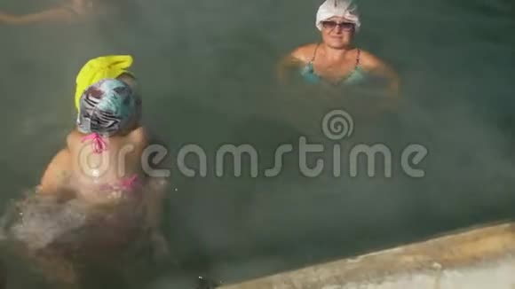 小女孩妈妈和奶奶在室外的传统水疗中心在热水盐水中游泳软软的视频的预览图