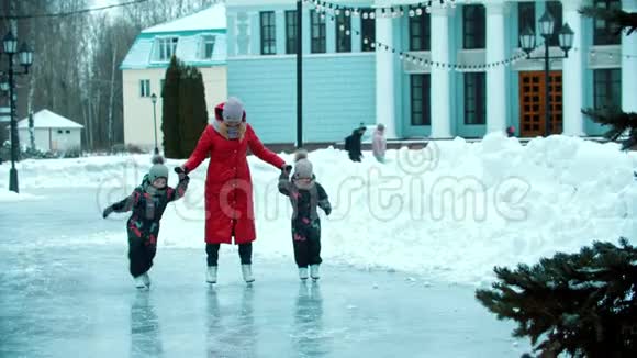 一家年轻的母亲和两个孩子在公共冰场上滑冰视频的预览图