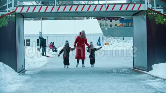 一家年轻的母亲和两个孩子在溜冰场上滑冰视频的预览图