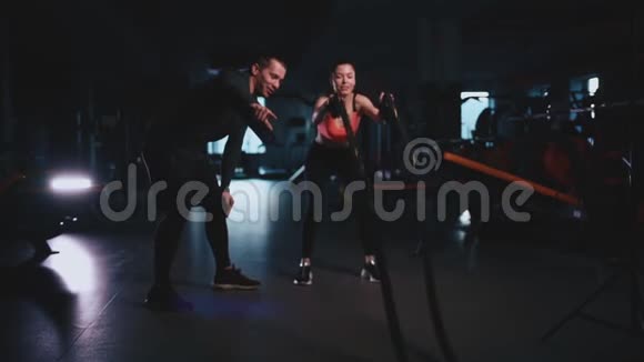 运动女性与私人教练在现代健身房锻炼绳索视频的预览图