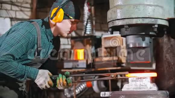 铁匠的工作在工业锻造机的压力下放置较长的金属热片视频的预览图