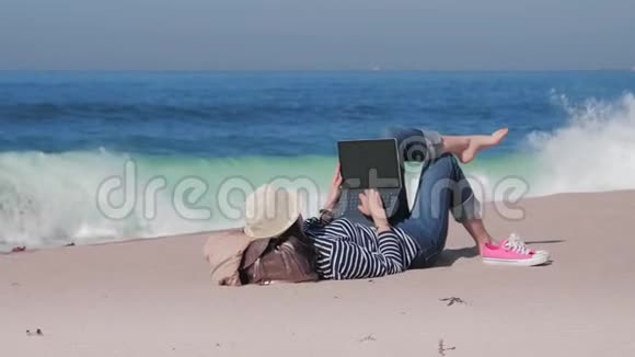 女人躺在沙滩上在外面工作视频的预览图