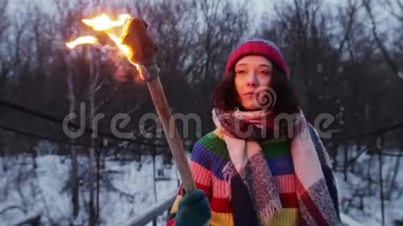 一个年轻的女人拿着火把走在森林里的雪桥上视频的预览图