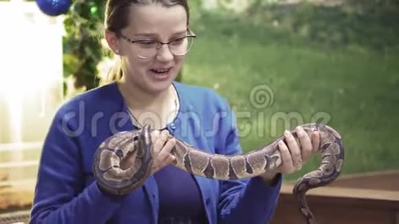 大自然女孩在动物园里抱着蛇享受野生动物保护区的远足学生在那里玩学习爬行动物4k视频的预览图