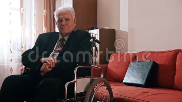 年迈的祖父悲伤的祖父坐在轮椅上看着摄像机视频的预览图