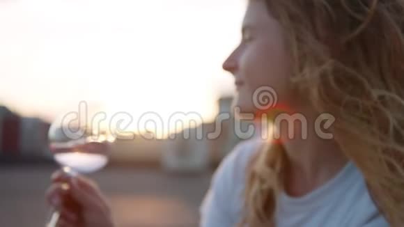 年轻女子在屋顶日落时喝玫瑰酒视频的预览图