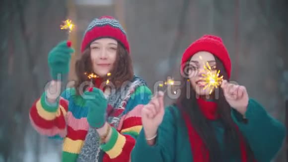 两个年轻的微笑的女人在冬天在户外跳舞点燃了火花视频的预览图