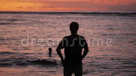 人类的剪影举起双手站在美丽的热带海滩上在红色的夕阳下自由概念视频的预览图