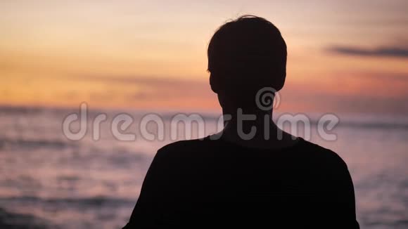 幸福男人的剪影举起双手站在美丽的热带海滩上在红色的日落自由概念视频的预览图