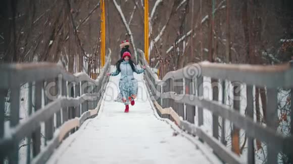 两个年轻的女人在雪桥上嬉戏奔跑视频的预览图