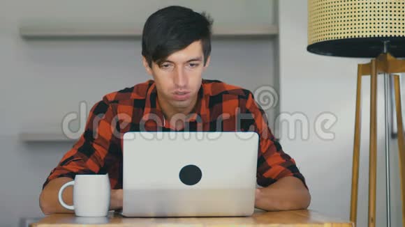 自信的商人自由职业者在笔记本电脑上工作在家里的餐桌上喝咖啡视频的预览图