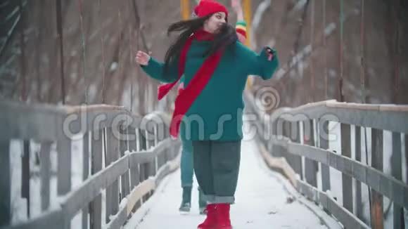 两个穿着五颜六色衣服的年轻女子在雪桥上玩得很开心视频的预览图