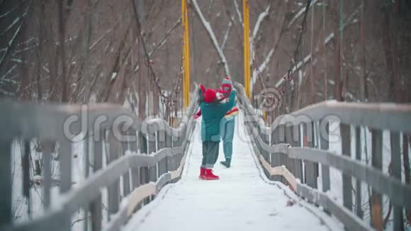 两个穿着五颜六色毛衣的年轻女人在雪桥上玩得很开心视频的预览图