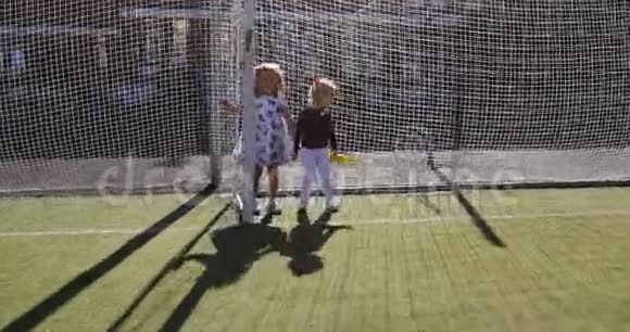 两个女孩在绿油油的人造草坪上嬉戏打闹视频的预览图