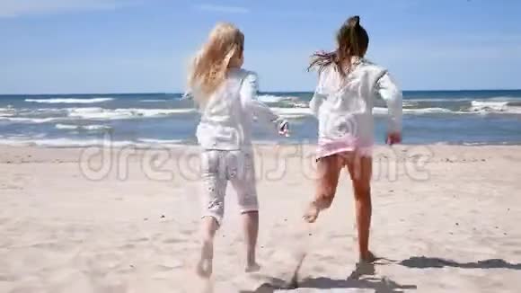 夏天海滩上的儿童肖像快乐的孩子们两个女孩跑去看在沙滩上玩得开心视频的预览图