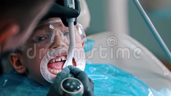 一个小男孩在现代牙科中进行清洁治疗用吸管从嘴里收集水视频的预览图