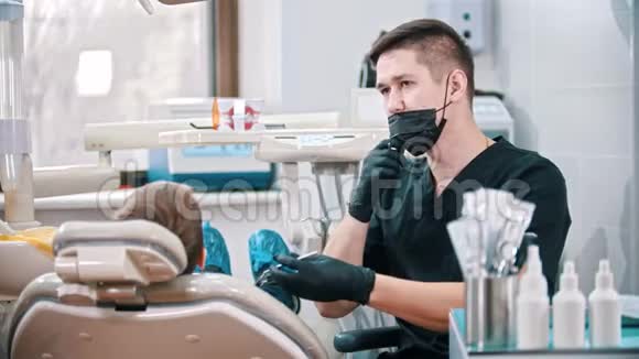 年轻的牙医在检查一个男孩的嘴之前戴上口罩视频的预览图
