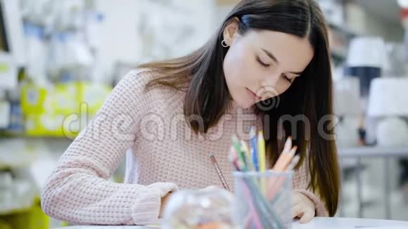 那个女孩坐在桌子旁拿着卡拉多克斯画画视频的预览图