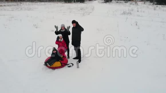 一家人站在雪场的中间向摄像机挥动双手那个坐在充气的小男孩视频的预览图