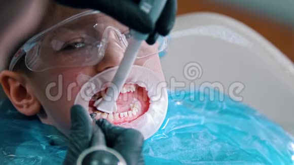 一个戴防护眼镜的小男孩在现代牙科中进行清洁治疗用吸管收集水视频的预览图