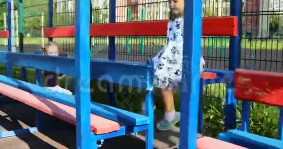 两个快乐的小女孩在院子里的长凳上玩耍视频的预览图