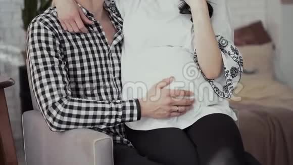 穿灰色衬衫的肌肉男手摸怀孕的妻子的肚子视频的预览图