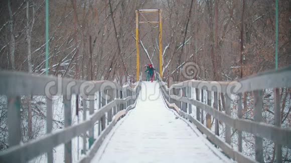 两个穿着鲜艳衣服的年轻快乐女人在雪桥上奔跑视频的预览图