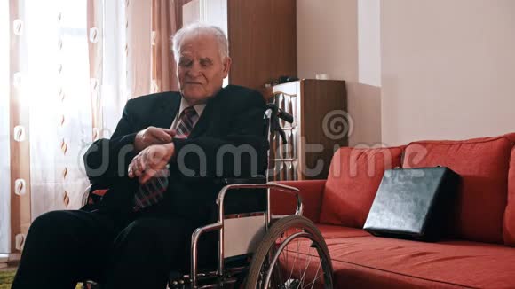 年迈的祖父祖父坐在轮椅上用手表检查时间视频的预览图