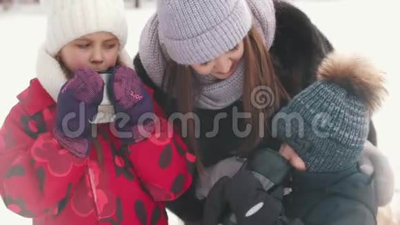 一位年轻女子和她的孩子们在户外喝热饮料视频的预览图