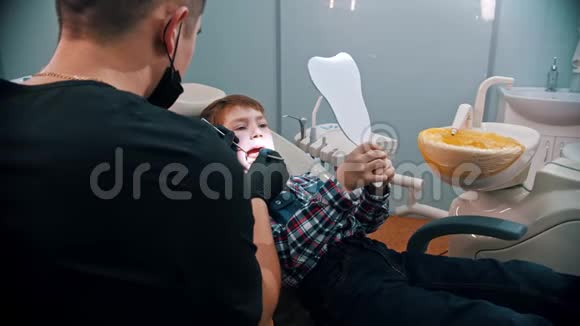一个正在牙科治疗的小男孩拿着镜子看着在做什么视频的预览图
