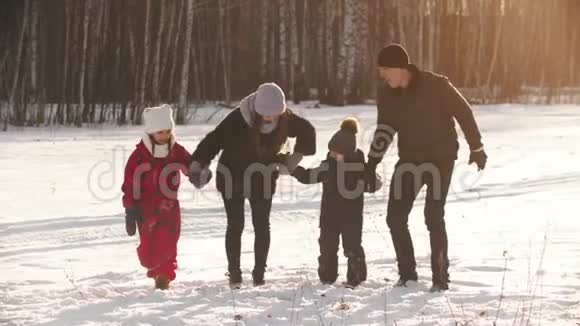 一个年轻幸福的家庭牵手跳跃冬天视频的预览图