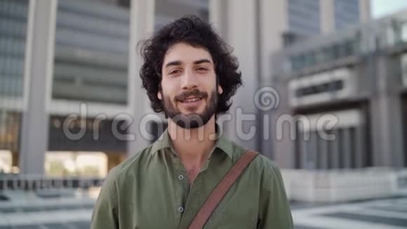 一位微笑的年轻职业男子站在公司大楼前看镜头的肖像视频的预览图