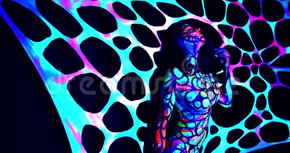 性感的女人站在五颜六色的房间里身体艺术在紫外线下发光4K视频的预览图
