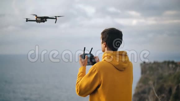 青年无人机飞行员的后视镜控制着一架飞行的四架直升机四重直升机拍摄大自然视频的预览图