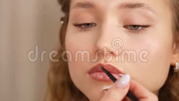 一个年轻女孩的脸化妆在女孩的嘴唇上涂上油漆视频的预览图