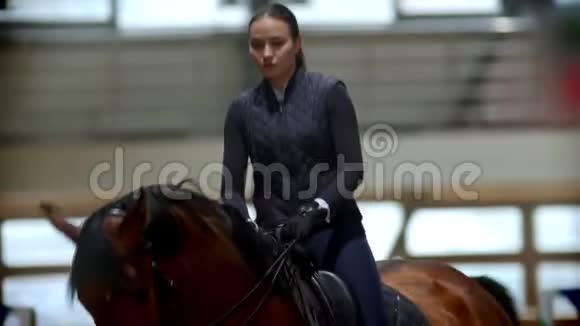 年轻女子骑着一匹深棕色的马骑在马棚视频的预览图