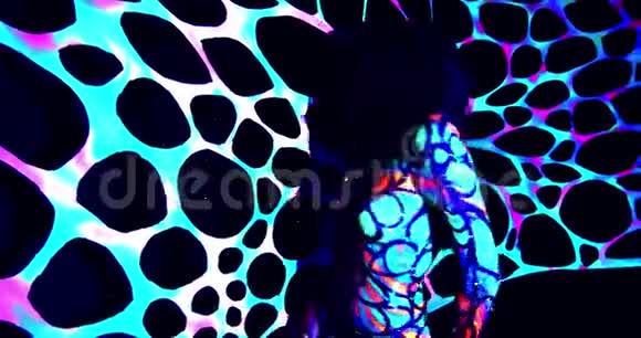 穿着五颜六色的身体艺术和化妆的女人在紫外线下跳舞视频的预览图
