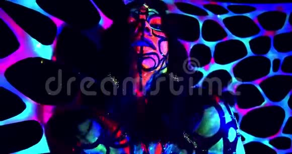 性感的女人拥有五颜六色的紫外线身体艺术在黑暗中摆姿势发光4K视频的预览图