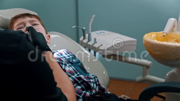 一个压力很大的小男孩在牙科诊所里擦牙吐出水来视频的预览图