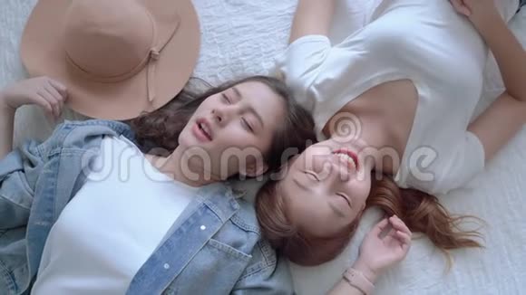 两个美丽的亚洲女孩的顶级视频谁是朋友躺在床上聊天心情愉快友谊的概念视频的预览图